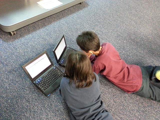 two children watching movies on computers