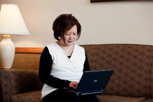 Woman working on genealogy blog on sofa
