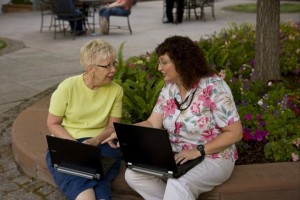 Two women indexing on laptops at a park