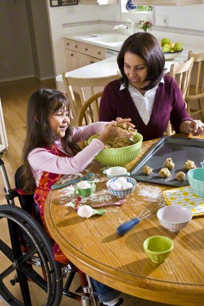 girl in wheelchair baking with mother