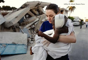 woman carrying injured child in Haiti after earthquake