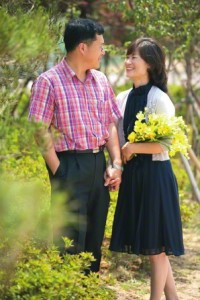 Couple outside, woman holding flowers.