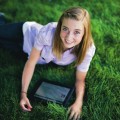 Young woman using iPad on the lawn.