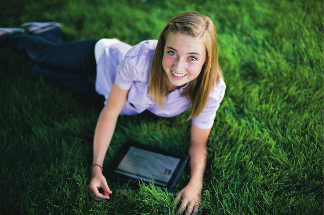 Young woman using iPad on the lawn.