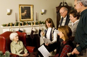 People singing Christmas carols to an elderly woman