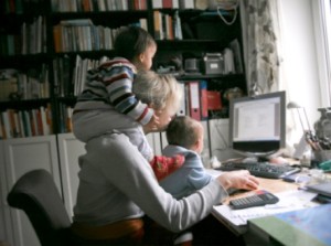 mom working at computer with toddlers hanging on