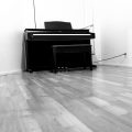 still black and white picture of a piano sitting alone in an empty room